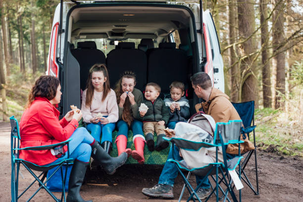 Eating Their Packed Lunch Family on a day out in Thrunton woods together in the North East of England in Autumn. They are sitting together in the boot of a van eating a picnic/packed lunch. northern europe family car stock pictures, royalty-free photos & images