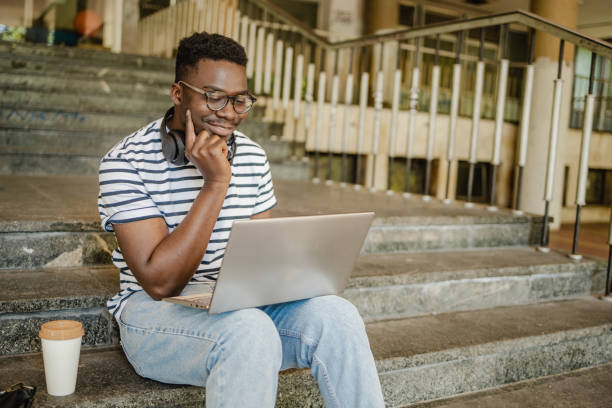 istock Young man is using laptop in front of the University 1339293889