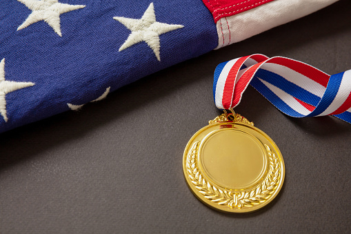 Medal gold for USA. Winner prize award with ribbon and US flag on black background. American athlete trophy in sport for first place champion. Blank space and laurel wreath, template