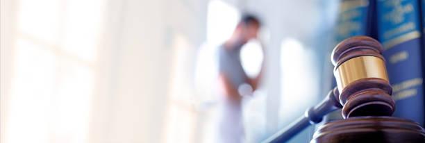 Stress Of Litigation A man stands out of focus in the background behind a gavel and several law books. The blurred room he stands in provides ample room for copy or text. lawsuit stock pictures, royalty-free photos & images