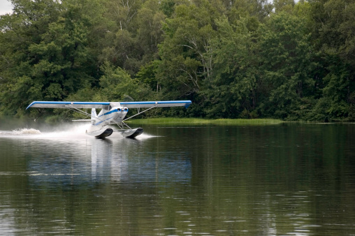 A pontoon plane lands on the water of a river.