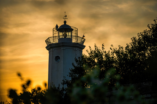 tower of an ancient lighthouse,  overgrown with wild bushes, on the shores of the Belosarayskaya Spit  in the Sea of Azov, Mariupol, Ukraine. Serene evening landscape and ancient architecture from the 19th century