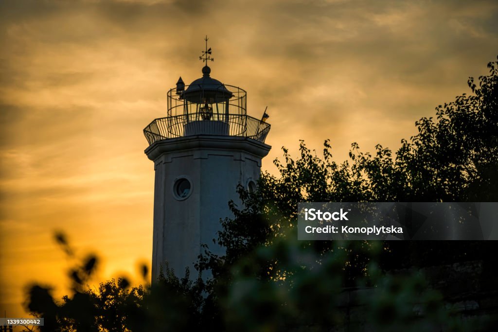 Tower of the old lighthouse against the evening sky tower of an ancient lighthouse,  overgrown with wild bushes, on the shores of the Belosarayskaya Spit  in the Sea of Azov, Mariupol, Ukraine. Serene evening landscape and ancient architecture from the 19th century Mariupol Stock Photo