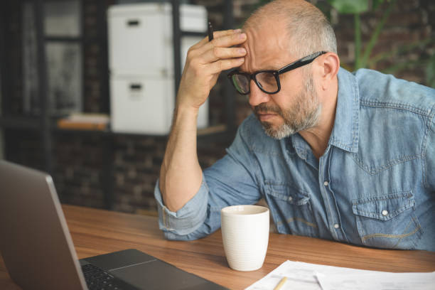 istock mature adult man working from office ( with laptop, paperwork, Negative Emotion) 1339303496