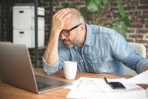 istock mature adult man working from office ( with laptop, paperwork, Negative Emotion) 1339303744
