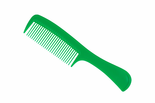 Close up photography of beautiful clean empty green color new plastic comb and equipment of hairdresser isolated on white background. Hairbrush is human personal accessory for hairstyle using everyday.