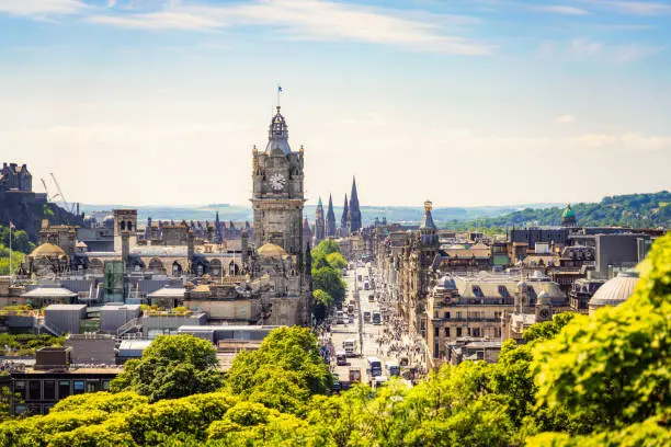 A high angle view over central Edinburgh, with Princes Street busy with pedestrians on a sunny afternoon.