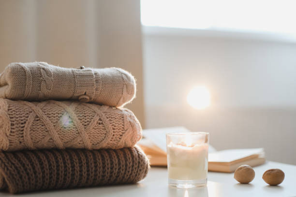 cozy comfortable home atmosphere and winter still life with a candle, book and knitted clothes cozy home atmosphere and still life with a cup, candle, book and sweaters on a table. winter still life stock pictures, royalty-free photos & images