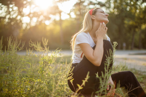 Woman sitting outdoors and suffering from pollen allergy One young woman in nature among ragweed plant scratch herself because she has a rash and problem with pollen allergy at summer. ragweed stock pictures, royalty-free photos & images