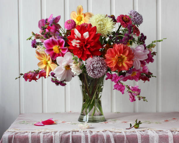 bright autumn bouquet of dahlias and asters on the table bright autumn bouquet of dahlias and asters on the table near the white wall rustic interior flowers in a glass vase flower arrangement stock pictures, royalty-free photos & images
