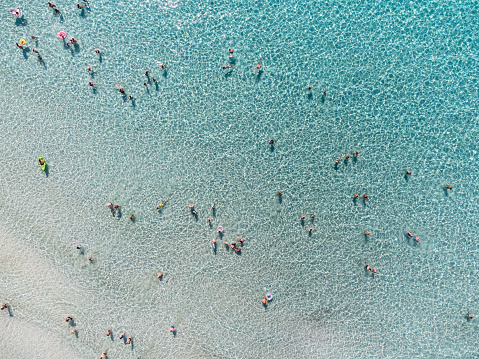 Aerial view of many people in a transparent turquoise sea. Unrecognizable people.