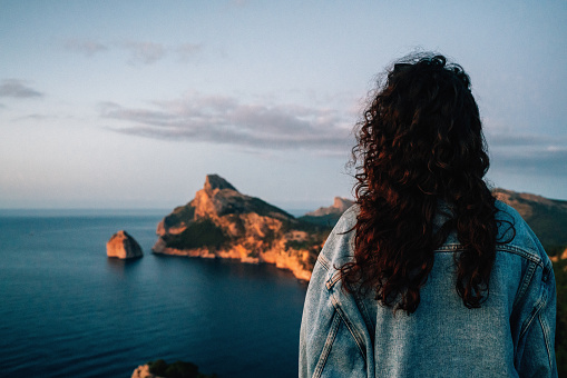A woman is admiring Cap de Formentor at sunset, Palma de Mallorca Island. Balearic Islands.