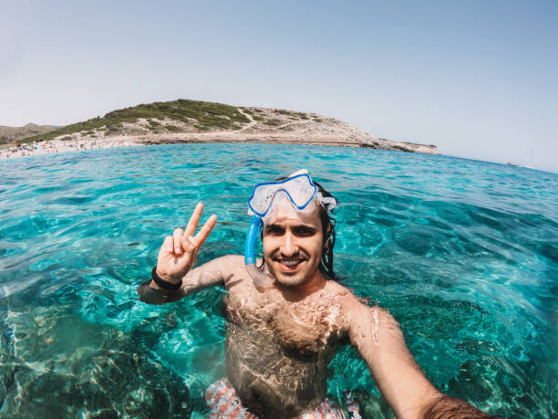 A man is taking a selfie while he's swimming in the sea. He's enjoying his vacation.