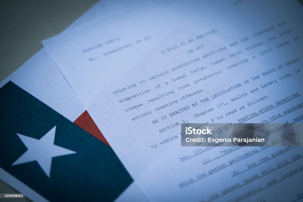 Close up view of Texas Abortion Law (TX SB8) next to the flag of Texas state. Blurred Close up view of Texas Abortion Law (TX SB8) next to the flag of Texas state. Abortion Stock Photo