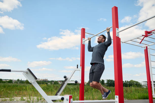 handsome muscular built mature european caucasian sportsman working out on crossbar outdoors in summer sportsground. concept of healthy active lifestyle, workout in open air, fitness and body building - playing field effort outdoors human age imagens e fotografias de stock