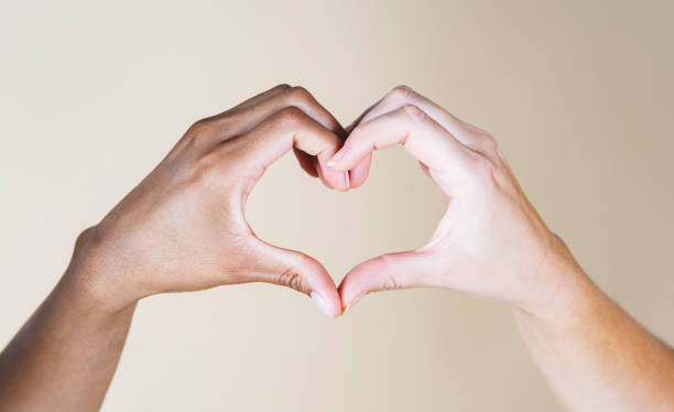 istock African hand and Caucasian hand make heart, beige background 1339319250