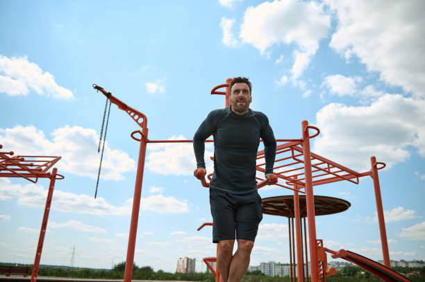 istock A middle-aged Caucasian European handsome man with an athletic build pulls himself up on a horizontal bar on a summer sportsground while training in the open air. Active and healthy lifestyle concept 1339319301
