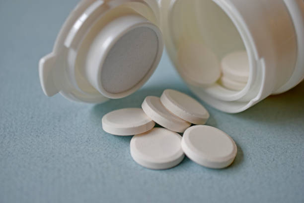 istock White flat medicine tablets on a blue background 1339324622