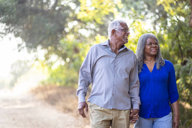 pareja negra mayor caminando por un sendero natural - men gray hair vitality healthy lifestyle fotografías e imágenes de stock