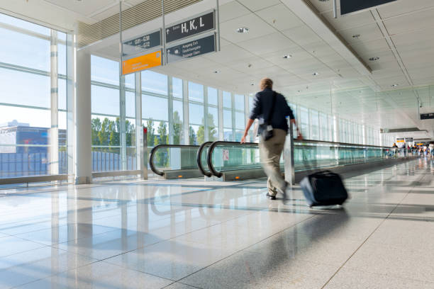 tourist with baggage walking on moving walkway in  airport, subject out of focus - elevated walkway imagens e fotografias de stock