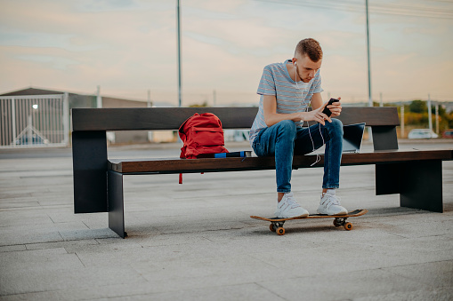 College student sitting outside on bench using mobile phone