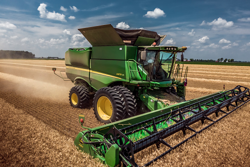 Henry County, Ohio - July 4, 2020:  A low drone photo of a farmer working in a wheat field in rural Ohio on a sunny summer afternoon harvesting the wheat with a John Deere S670 combine