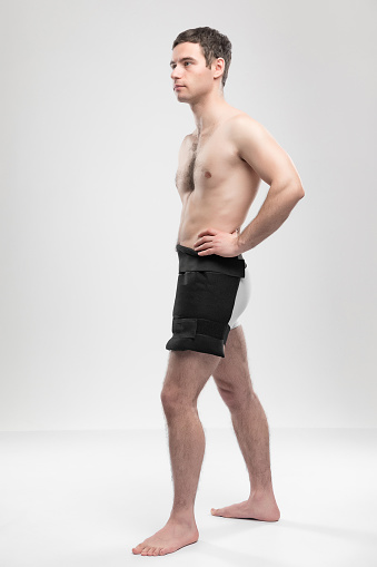 Studio portrait of adult sports man with reusable post-injury ice-pack with liquid gel. Rehabilitation and recovery concept with copy space
