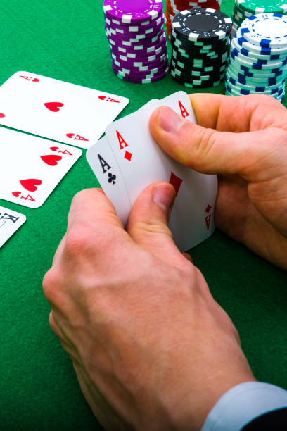 A man shows his deck of aces during a poker game, vertical photo, green background. stock photo