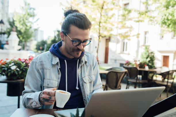 istock Young man at the cafe enjoying coffee and working on laptop 1339342377