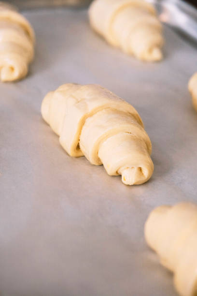 istock Close-up on a group of croissant dough on tray before putting into oven. Manufacturing process of french food 1339343994