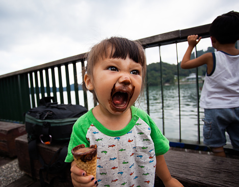 Cute young girl hyped up on too much sugar with chocolate ice cream all over her mouth.