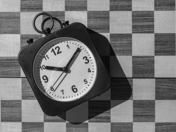 istock Clock with hands on the background of a black-and-white chessboard. Flat lay. 1339380037