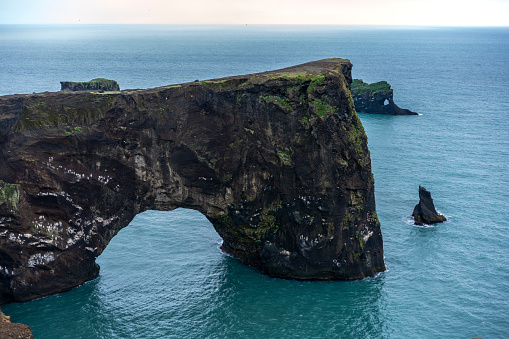 Rocks in water near Reynisfjara black sand beach on cloudy and rainy weather. It is beach in Southern Iceland known for Gardar basalt columns