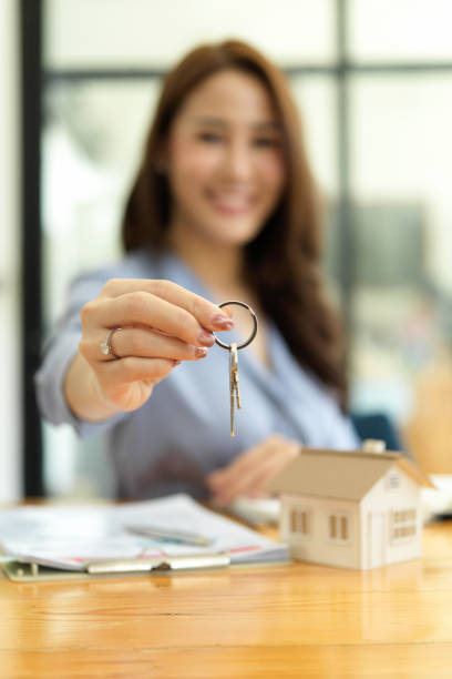 istock Focused hands, Beautiful real estate agent holding house key 1339384847