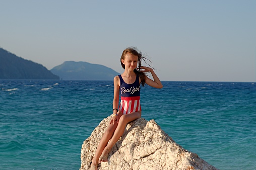 Little girl in a bright swimsuit on a background of the sea