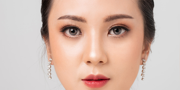 Asian female Eye with Extreme Long False Eyelashes. Eyelash Extensions. Makeup, Cosmetics, Close up macro eye woman. Cosmetic contact lenses. Closeup face asian woman perfect skin.