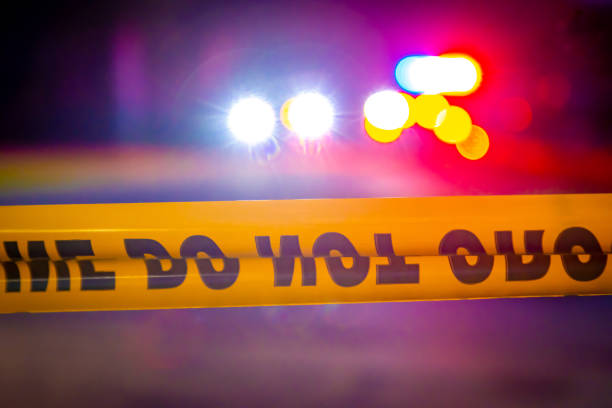 Generic police lights and yellow police tape at crime scene Generic and blurry police lights from a cruiser vehicle and car headlights behind yellow crime scene do not cross caution tape at night. police vehicle lighting stock pictures, royalty-free photos & images