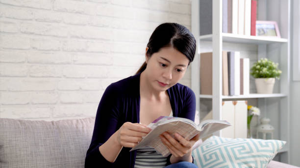 istock asian female student reading book sitting on sofa 1339402533