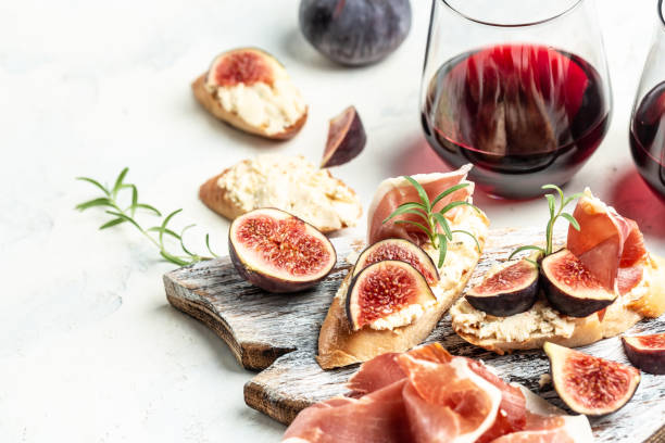 Appetizers, Sandwich with prosciutto, cream cheese and figs. antipasti snacks and red wine in glasses. Authentic traditional spanish tapas set. Top view stock photo