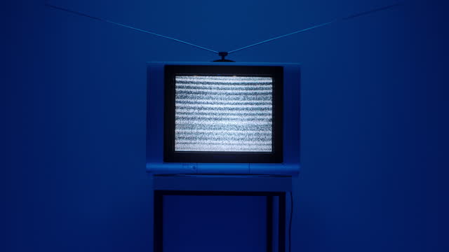 A TV with a TV screen noise in the middle of the frame on a dark blue background