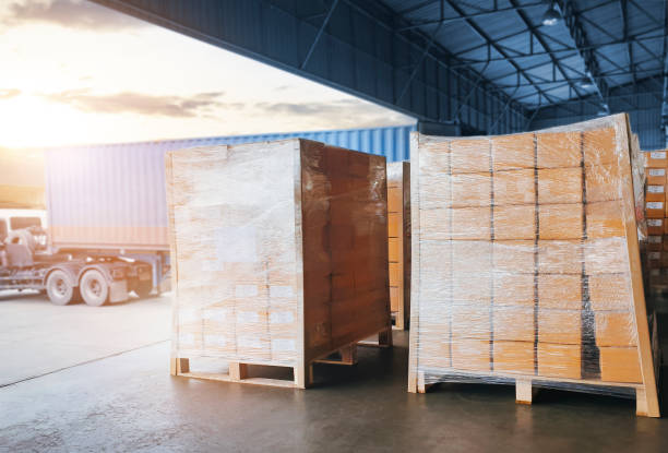 istock Stacked of Package Boxes Wrapped Plastic Film on Pallets Load with Shipping Cargo Container. Truck Parked Loading at Dock Warehouse. Delivery. Warehouse Logistics. Cargo Freight Truck Transportation. 1339407990