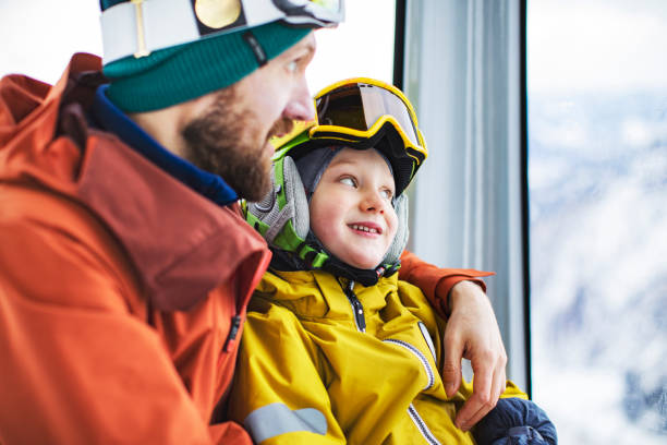 father with son in ski lift at ski resort - family skiing ski vacations imagens e fotografias de stock