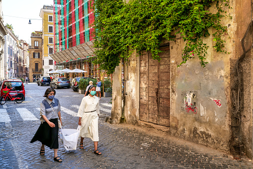 Rome, Italy, September 07 -- Two Catholic nuns of Asian ethnicity walk along an alley of the Rione Monti (Monti district) in the historic heart of Rome. The Monti district is a popular and multi-ethnic quarter much loved by the younger generations and tourists for the presence of trendy pubs, fashion shops and restaurants, where you can find the true soul of the Eternal City. This district, located between the Esquiline Hill and the Roman Forum, is also rich in numerous Baroque-style churches and archaeological remains from the Roman era. In 1980 the historic center of Rome was declared a World Heritage Site by Unesco. Image in high definition format.