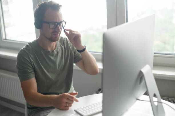 istock A confident male freelancer sitting at the desk with a laptop, using headset 1339410997