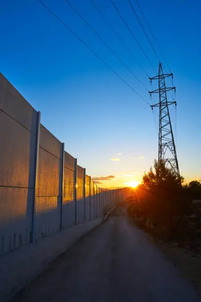 Sunset in a track with electric tower and concrete wall