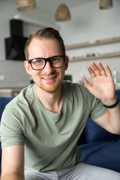 istock A cheerful guy is waving hello into webcam, smiles and greeting 1339412130