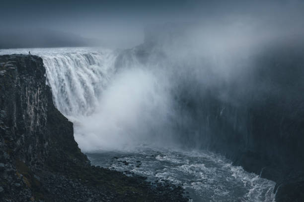 Man standing on top of majestic Dettifoss waterfall in north Iceland.