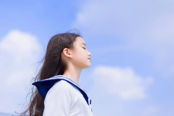 Side view of student girl enjoying summer breeze , smiling with eyes closed stock photo