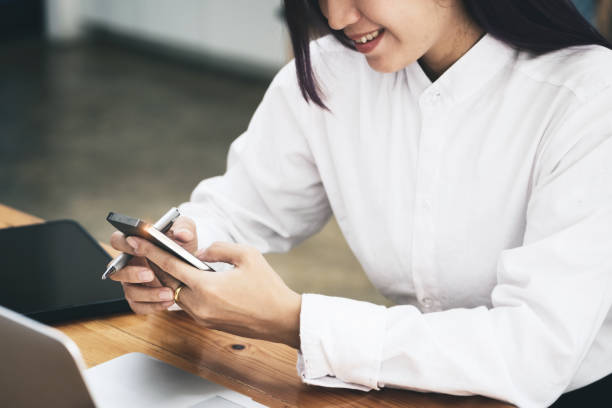 istock woman using mobile phone and computer to work in home office. 1339415296