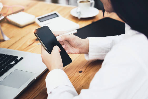istock woman using mobile phone and computer to work in home office. 1339415357